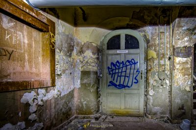 Eine Tür in einem heruntergekommenen Gebäude mit Graffiti darauf