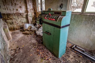 Ein schmutziges Zimmer mit einer grünen Maschine und einem Mülleimer