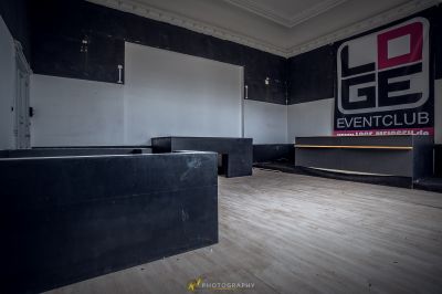 Ein Zimmer mit einem schwarz-weißen Schild und einem Holzboden