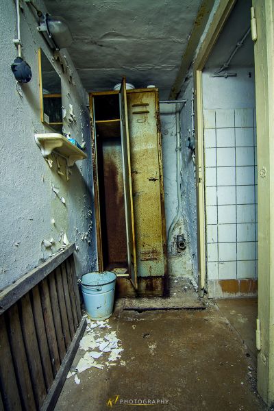 Ein schmutziges Badezimmer mit einer kaputten Tür und einer Toilette