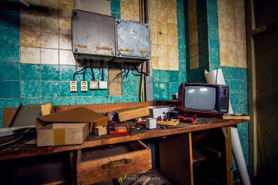 Ein überladener Schreibtisch mit einem Fernseher und einer Box mit Werkzeugen