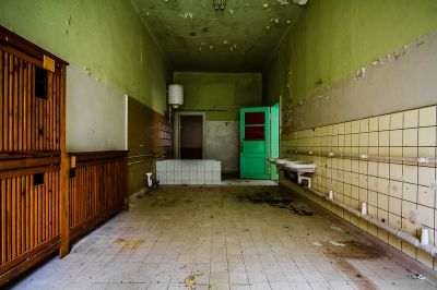 Ein schmutziges Badezimmer mit einer grünen Tür und einer weißen Toilette