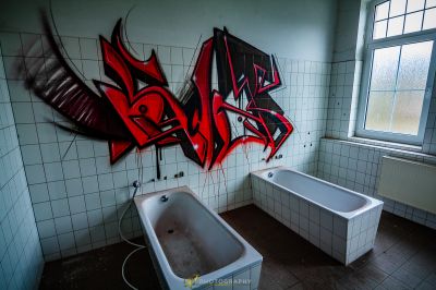 Ein Badezimmer mit Badewanne und Graffiti an der Wand