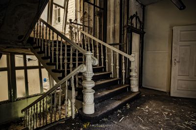 Eine Treppe mit einem kaputten Geländer und einer kaputten Tür