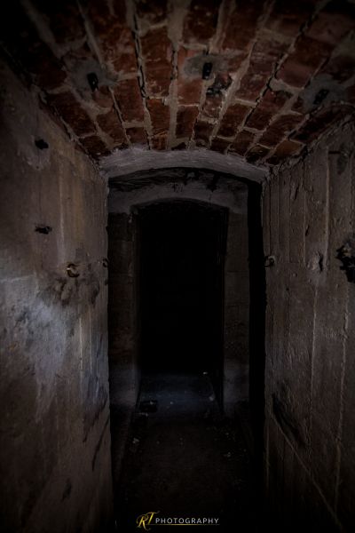 Einen dunklen Flur mit einer Ziegeldecke und einem Licht am Ende