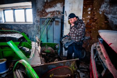 Ein Mann steht in einem Zimmer mit einem kaputten Auto