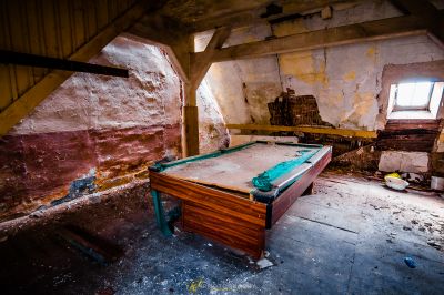 Ein Zimmer mit einem Billardtisch und einem Stuhl