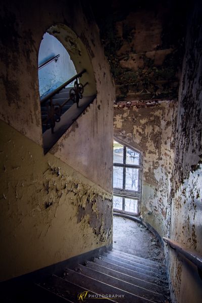 Eine Treppe in einem verlassenen Gebäude mit einer zerbrochenen Tür