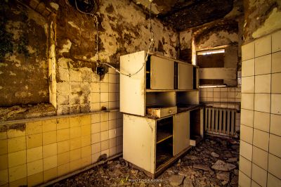 Eine schmutzige Küche mit einem kaputten Kühlschrank und einer schmutzigen Wand