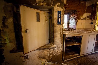 Eine schmutzige Küche mit einem kaputten Kühlschrank und einem schmutzigen Herd