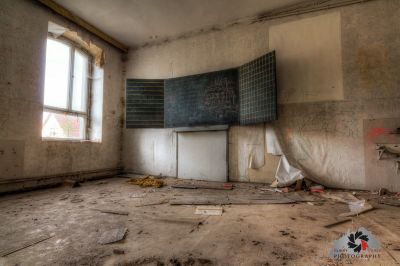 Ein Zimmer mit einer Kreidetafel und einem zerbrochenen Fenster