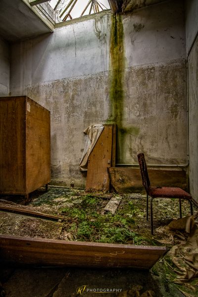 Ein Zimmer mit einem Stuhl und einem kaputten Kühlschrank