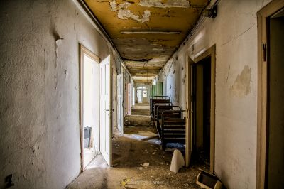 Einen Flur mit einer kaputten Tür und einem Stuhl