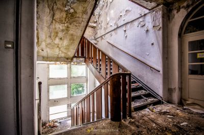 Eine Treppe in einem verlassenen Gebäude mit einer zerbrochenen Tür