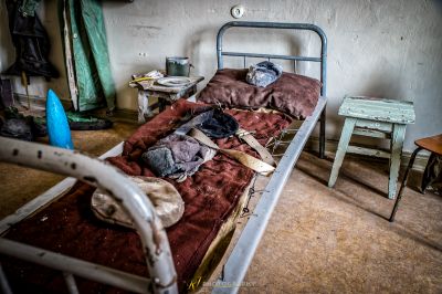 Ein Bett mit einer roten Decke und einem Stuhl