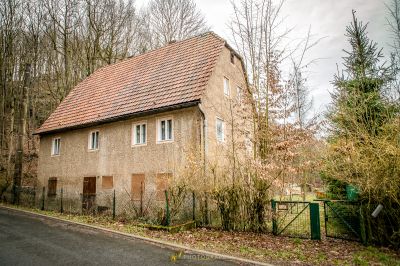 Ein Haus mit einem roten Dach und einem grünen Tor