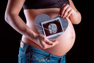 Eine schwangere Frau, die eine Tablette mit einem Bild von ihrem Baby hält