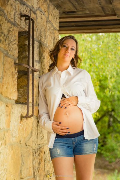 Eine schwangere Frau, die vor einer Steinmauer steht