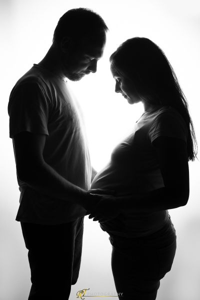 Ein schwangeres Paar, das im Licht steht