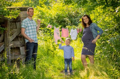 Eine dreiköpfige Familie, die auf einem Feld Kleider aushängt