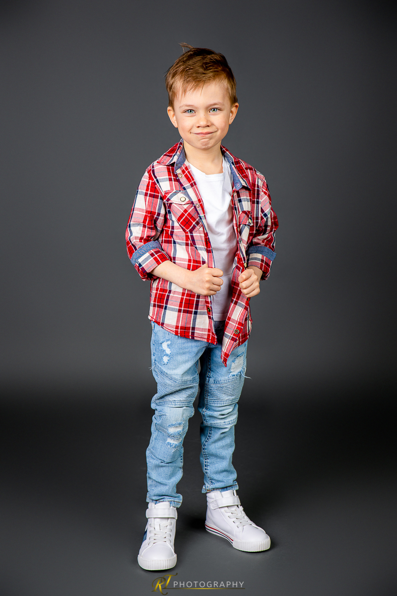 Ein kleiner Junge steht in einem Studio mit den Händen in den Taschen