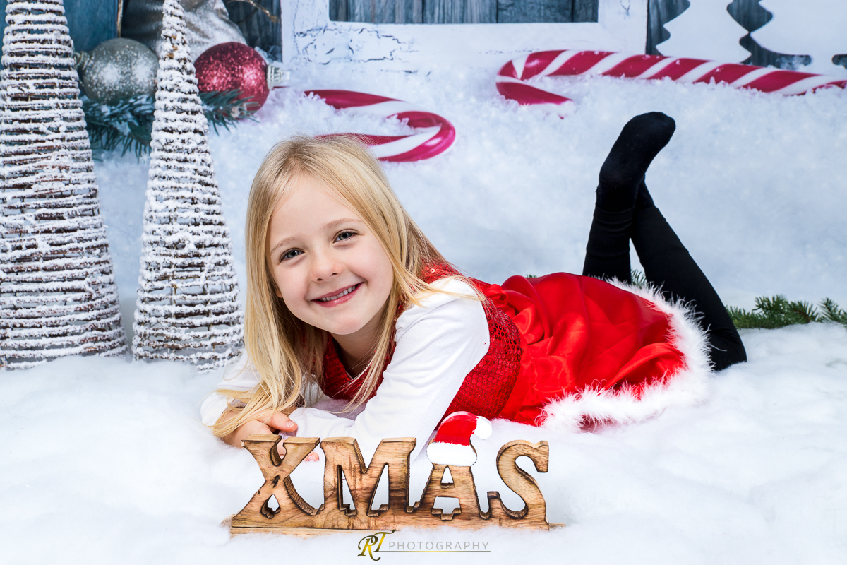 Ein kleines Mädchen liegt im Schnee mit einem Santa Hut