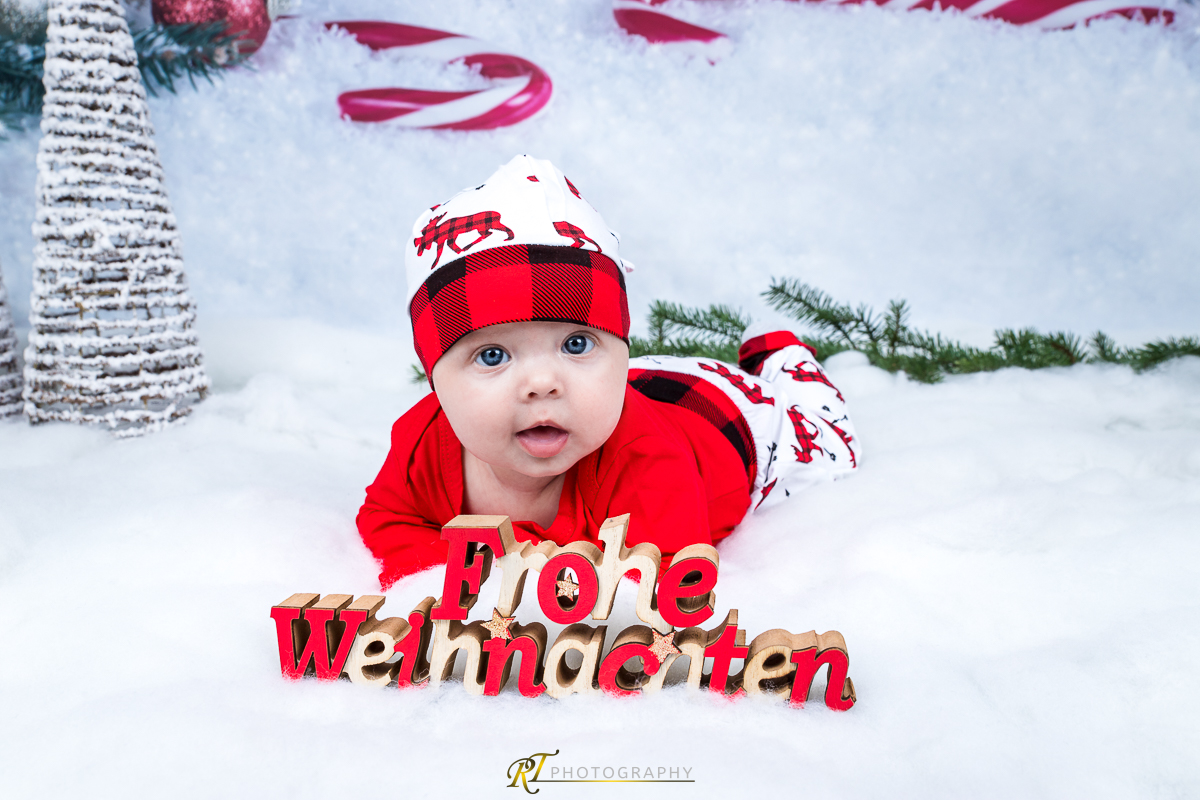 Ein Baby liegt im Schnee mit einem Weihnachtsschild