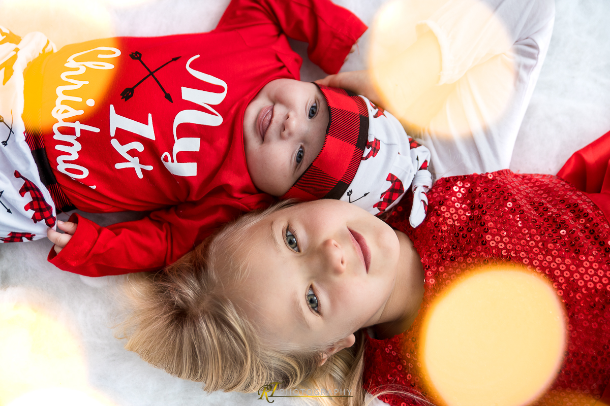Zwei Kinder, die auf einem Bett mit rotem Hut liegen