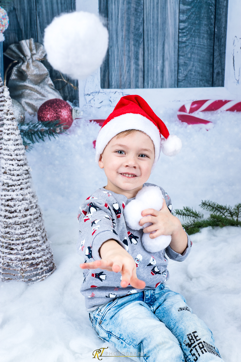 Ein kleiner Junge sitzt im Schnee mit einem Schneeball