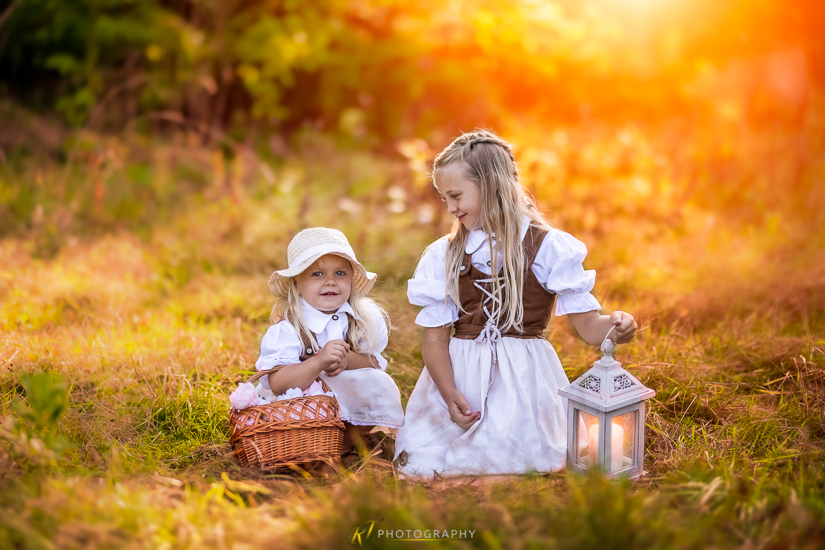 Zwei kleine Mädchen sitzen im Gras mit einer Laterne