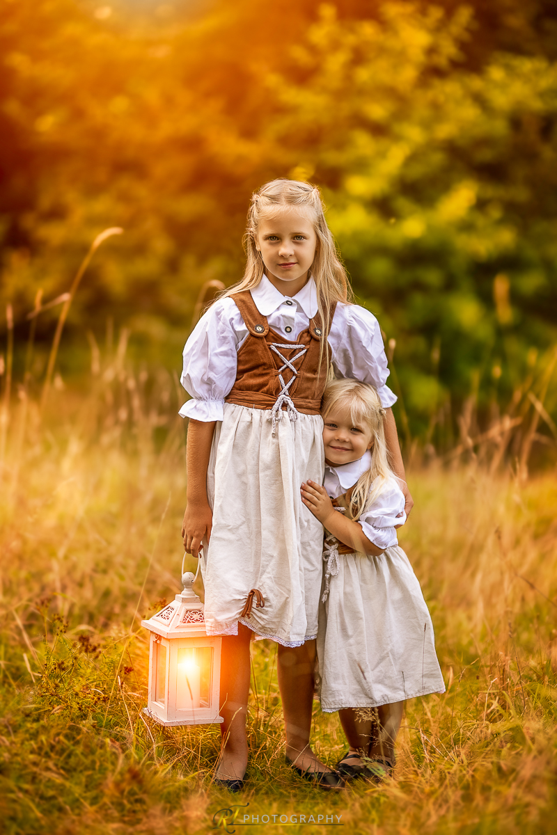 Zwei kleine Mädchen stehen auf einem Feld mit einer Laterne